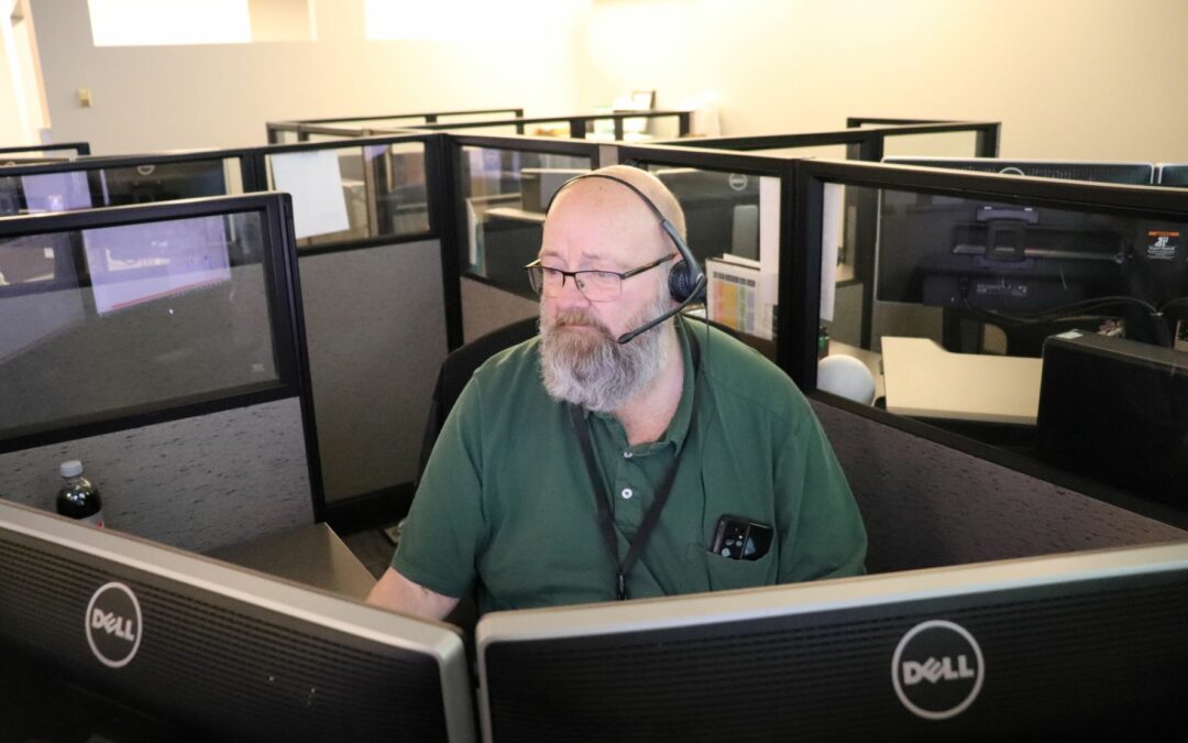 Jeff Strand at a desk wearing a phone headset.